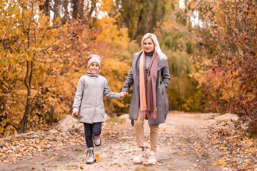 happy family mother and child daughter play and laugh at the autumn walk. Mother and child relations. Fashionable mother and daughter in a stylish look with the same jackets.