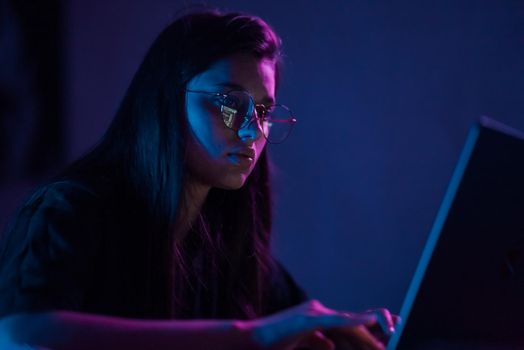 Attractive young woman working in home at night. Girl using laptop.