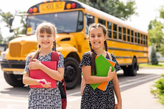 Portrait of two girls with school bags after lesson in school.