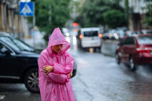 Sad woman in a raincoat on the street on a rainy day.