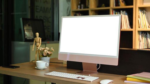 Contemporary workplace with computer pc, laptop, coffee cup and office supplies on wooden table. Blank screen for advertise text.