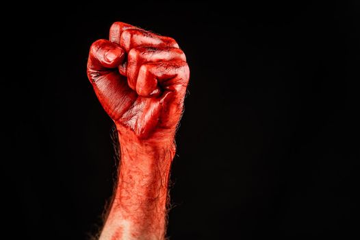 Bloody male fist on a black background. Copy space