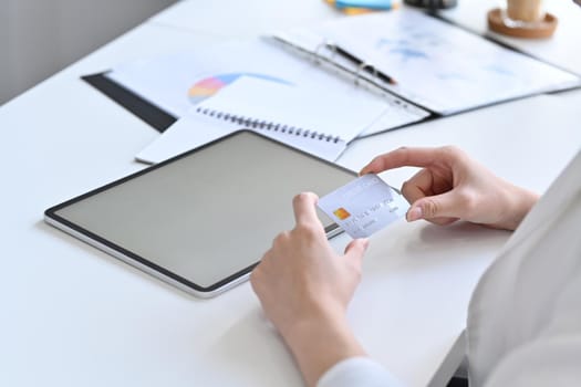 Young woman holding credit card and using digital tablet. Online shopping, e-commerce, internet banking concept.