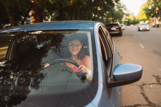 Beautiful Smiling woman driving car, attractive girl sitting in automobile, outdoors summer portrait.