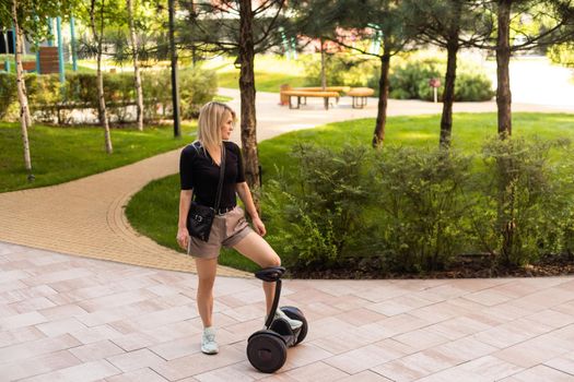 woman riding electric mini segway hover board scooter in green park. Good summer weather, ecological urban transportation technology and pretty model.Electric self-balancing scooter board.