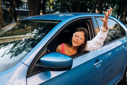 A young angry woman peeks out of the car window. A woman shows her displeasure