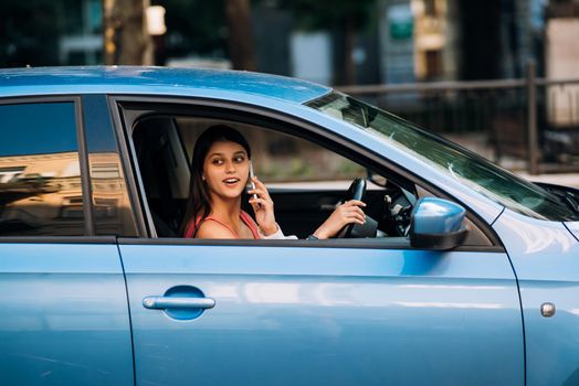 Business woman sitting in car and using her smartphone.