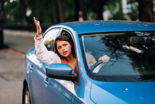 A young angry woman peeks out of the car window. A woman shows her displeasure