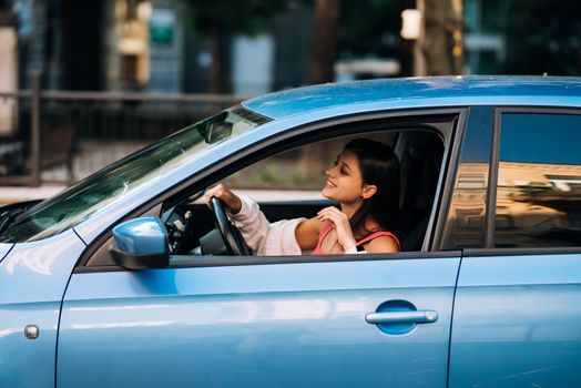 Beautiful Smiling woman driving car, attractive girl sitting in automobile, outdoors summer portrait.