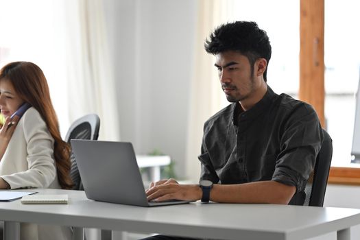 Man office worker is working, reading online information on laptop computer.