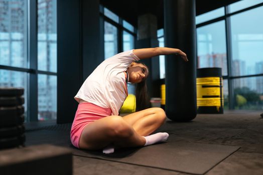 Young sporty woman practicing yoga, working out, wearing sportswear, indoor full length, yoga studio