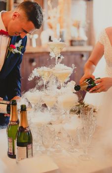 The bride and groom fill the champagne fountain. Wedding article. A happy couple. Love. Photos for printed products. Romance. Wedding catalog