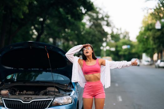 Woman with broken down car on the road she feeling serious and stressed. Look for someone help.