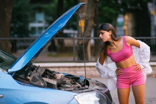 Woman with broken down car on the road she feeling serious and stressed. Look for someone help.