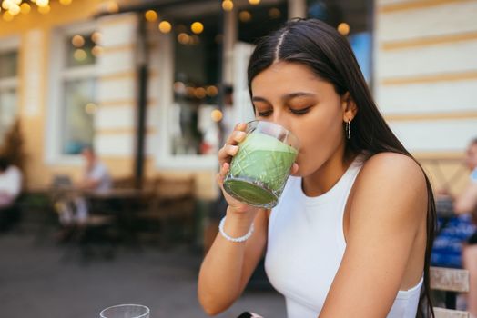 Woman in a cafe drinks a green drink ice latte.