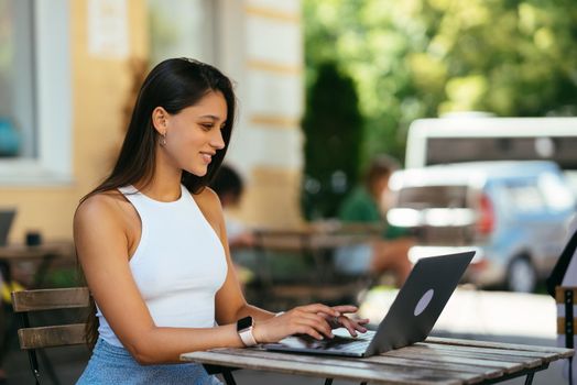 Woman working on laptop at outdoors cafe