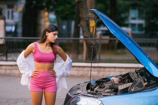 Woman with broken down car on the road she feeling serious and stressed. Look for someone help.