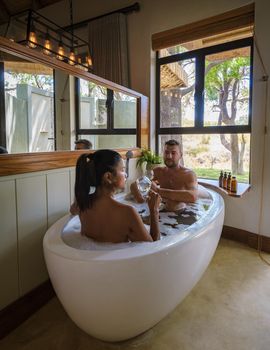 Men and women in a bath tub, a couple on safari in South Africa at a luxury safari lodge. men and women relaxing in bath