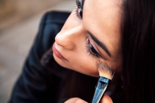 closeup of a young woman touching up her makeup, concept of beauty