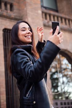 vertical photo of a happy young woman looking at her telephone at the street, concept of technology and communication
