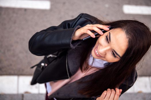 top view of a smiling woman calling on the phone in the street, concept of technology and urban lifestyle, copyspace for text