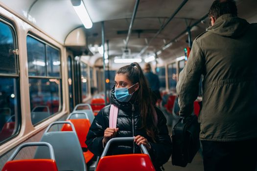 Young woman with mask traveling in the public transport by bus. Unique protective mask of the respiratory tract from coronavirus.