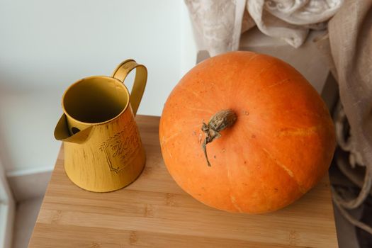 Autumn interior in a photo studio, with pumpkins, a vase and a wooden stool.