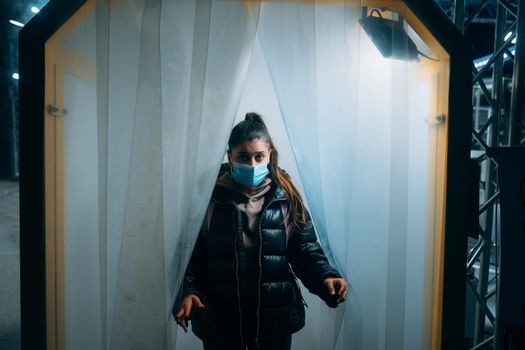 Young beautiful woman in a medic mask is staying in a disinfection tunnel