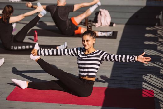 Yogi woman and diverse group of young sporty people practicing yoga, female students training at house's roof. Well being, wellness concept