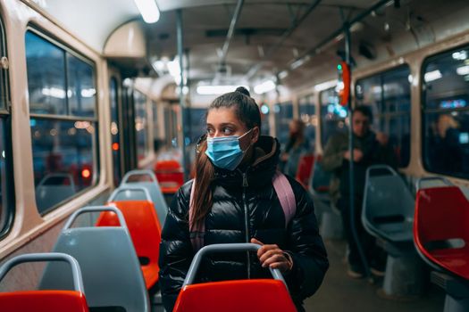 Young woman with mask traveling in the public transport by bus. Unique protective mask of the respiratory tract from coronavirus.