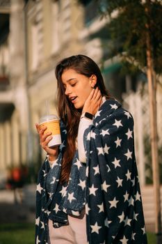 portrait of a young attractive woman in the park with a paper glass of coffee. Rest in the park