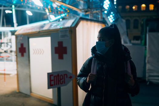 Young beautiful woman in a medic mask is staying at a disinfection tunnel