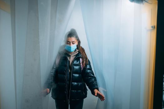 Young beautiful woman in a medic mask is staying in a disinfection tunnel