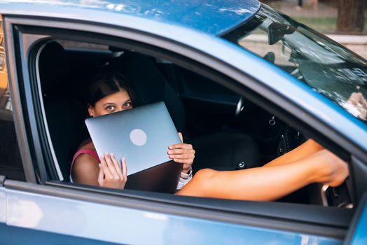 Young woman using laptop in her car. Close view