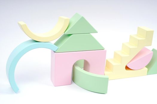 Abstract composition of wooden figures. Figures of yellow, pink, blue and green. The wooden children's cubes is isolated on a white background. Zero waste toy.