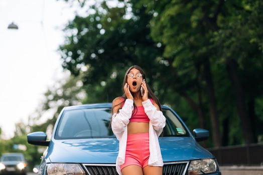 Woman talking on phone near car on road