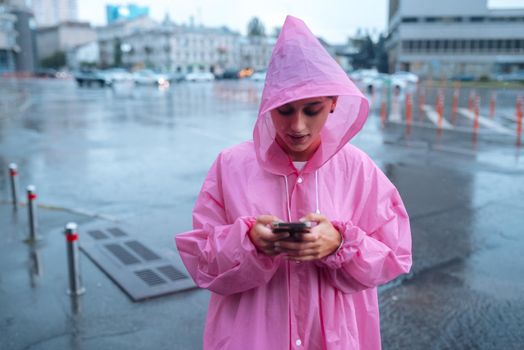 A young woman in a raincoat is waiting for someone in the rain