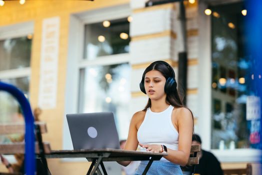 Woman working on laptop at outdoors cafe