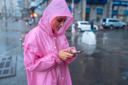 A young woman in a raincoat is waiting for someone in the rain