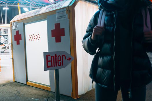 Young beautiful woman in a medic mask is staying at a disinfection tunnel