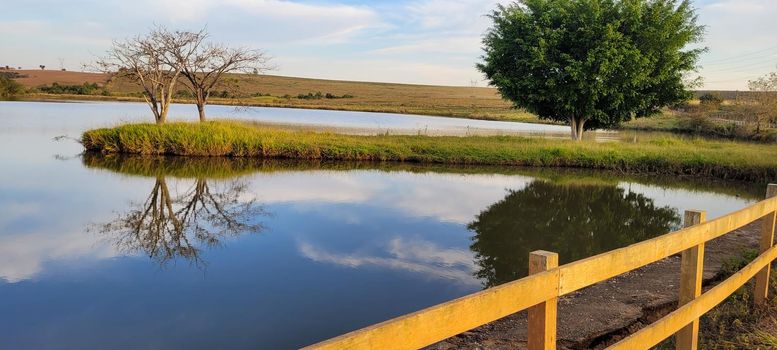 lake with a natural landscape of a farm in the countryside of Brazil with trees and lawn around it