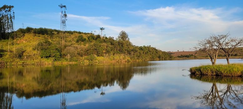 lake with a natural landscape of a farm in the countryside of Brazil with trees and lawn around it