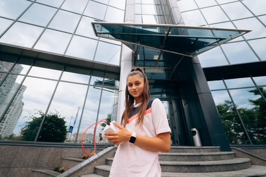 Sportswoman in good physical shape poses against modern building background outdoors walks in city