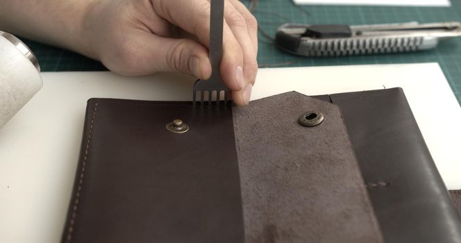 Man working with leather and makes a holes