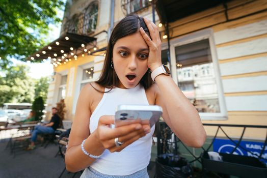 Pretty woman sitting on steps in an urban street to read an sms on her mobile phone, profile view