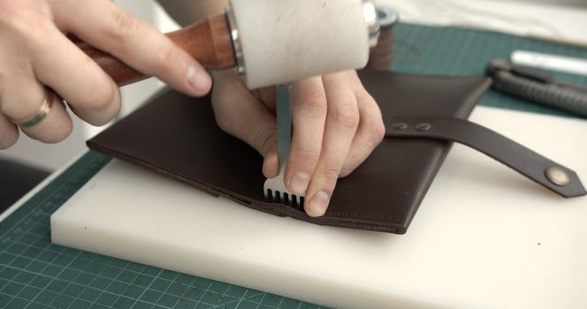 Making of brown handmade leather wallet. Sewing wallet. Piercer punches holes in a piece of skin