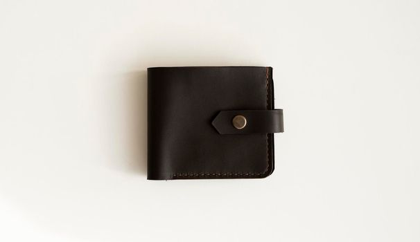 Top view of new dark brown genuine leather wallet with banknotes and credit card inside isolated on white background