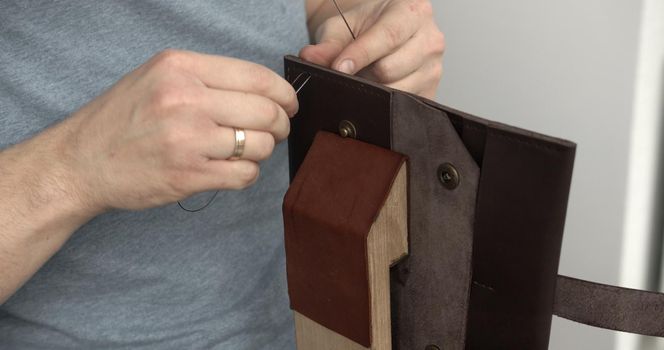 Sewing a brown leather wallet. Leather work. Sewing products by hand. Manufacture of leather goods