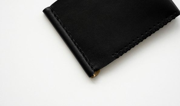 Black men's money clip handmade leather wallet for cards lies on a white table. Leather goods and accessory