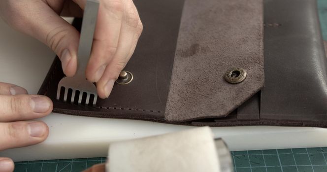 A man makes a handmade leather wallet from genuine leather